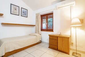 A bedroom with a bed, a wooden cabinet, a window with curtains, and wall-mounted pictures. - Apartment 'La Capannuccia D' with Sea View, Wi-Fi and Air Conditioning (Ansedonia)