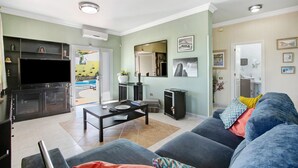 A living room with a sofa, coffee table, TV, and a dining area with a table and chairs. - Eveas – Private Villa with Pool in Tenerife (Candelaria)