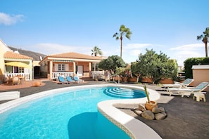 A swimming pool with lounge chairs, a small garden, and a building with a tiled roof. - Eveas – Private Villa with Pool in Tenerife (Candelaria)