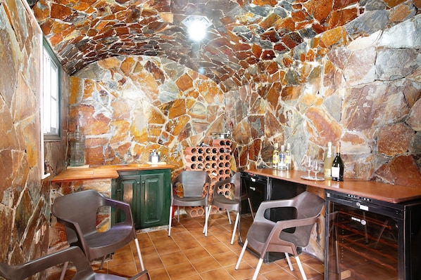 A stone-walled room with a wine rack, chairs, and a wine cooler. - Eveas – Private Villa with Pool in Tenerife (Candelaria)