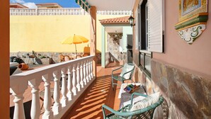 A balcony with a white balustrade, a stone wall, and a yellow umbrella. - Eveas – Private Villa with Pool in Tenerife (Candelaria)