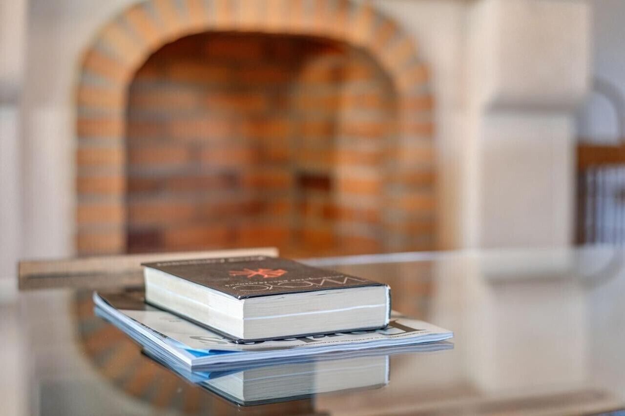 A book on a glass table with a brick fireplace in the background.