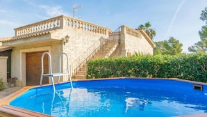 A swimming pool with a wooden deck, a stone building with a staircase, and a metal ladder. - Villa 'Ginebro Puerto Pollença' with Private Pool, Wi-Fi and Air Conditioning (Puerto Pollença)