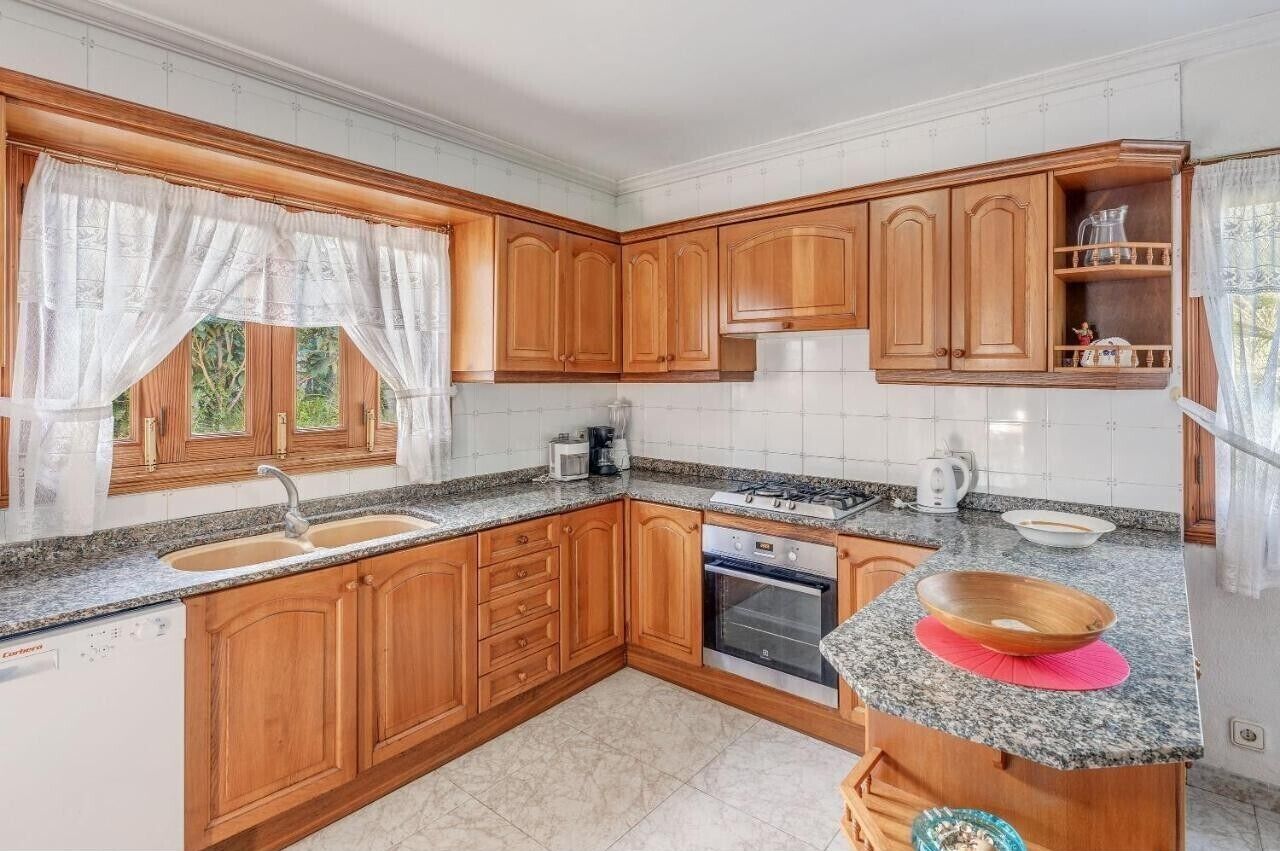 A kitchen with wooden cabinets, granite countertops, a dishwasher, and a stove.