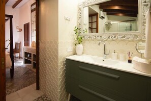 A bathroom with a white sink, a green vanity, a large mirror, and a potted plant.