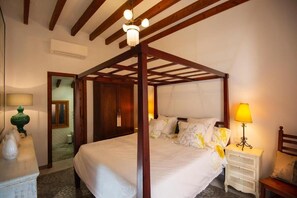 Un lit à baldaquin avec un cadre en bois, une table de chevet avec une lampe et un miroir au mur.