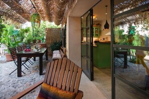 A patio with a table, chairs, and a woven ceiling.
