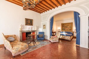 A room with a fireplace, two armchairs, a bed, and a painting on the wall. - Vacation Home "Residenza D'Epoca Alcova" with Shared Pool, Shared Garden & Wi-Fi (lucignano)