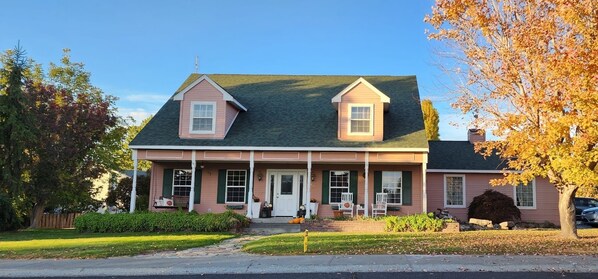 A two-story house with a front porch, a chimney, and a garage. - Alegria!  Five Bedroom Colonial Style Home Conveniently Located! Pet Friendly! (Moses Lake)