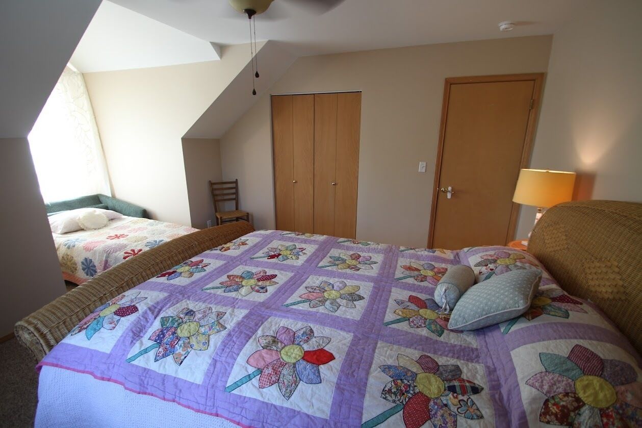 A bedroom with two beds, a wooden wardrobe, and a window with a view.