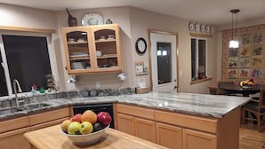 A kitchen with wooden cabinets, a marble countertop, and a fruit bowl on a wooden table. - Alegria!  Five Bedroom Colonial Style Home Conveniently Located! Pet Friendly! (Moses Lake)