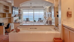 Un baño amplio con una bañera grande, ducha y vistas al mar a través de un ventanal.