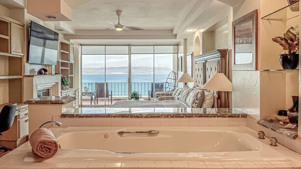 Un dormitorio amplio con ventana grande, bañera y balcón con vistas al mar.