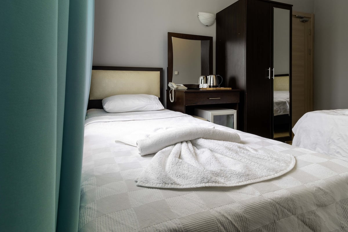 A hotel room with a bed, a desk with a telephone and a kettle, and a wardrobe.