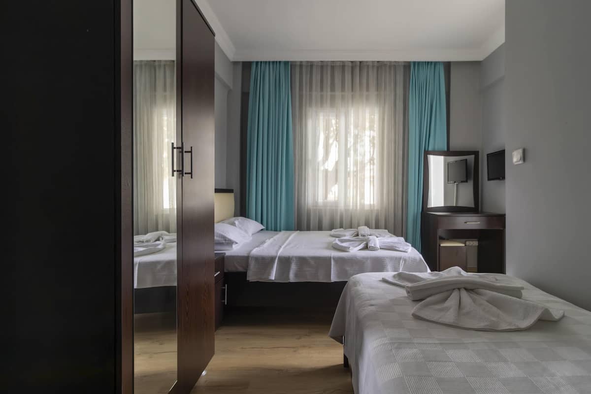 A hotel room with two beds, a desk, a chair, a TV, and a wardrobe.