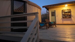 Eine Jurte mit Holzterrasse, Gäste-WC und Liegestühlen.