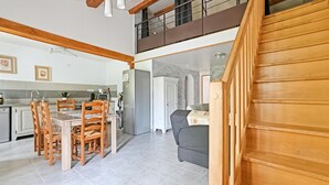 A spacious kitchen with a dining area, a refrigerator, and a staircase leading to an upper level. - 2 bedroom gorgeous apartment in Codognan (Codognan)