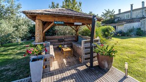 A wooden deck with a thatched roof structure, outdoor seating, and potted plants. - 2 bedroom gorgeous apartment in Codognan (Codognan)