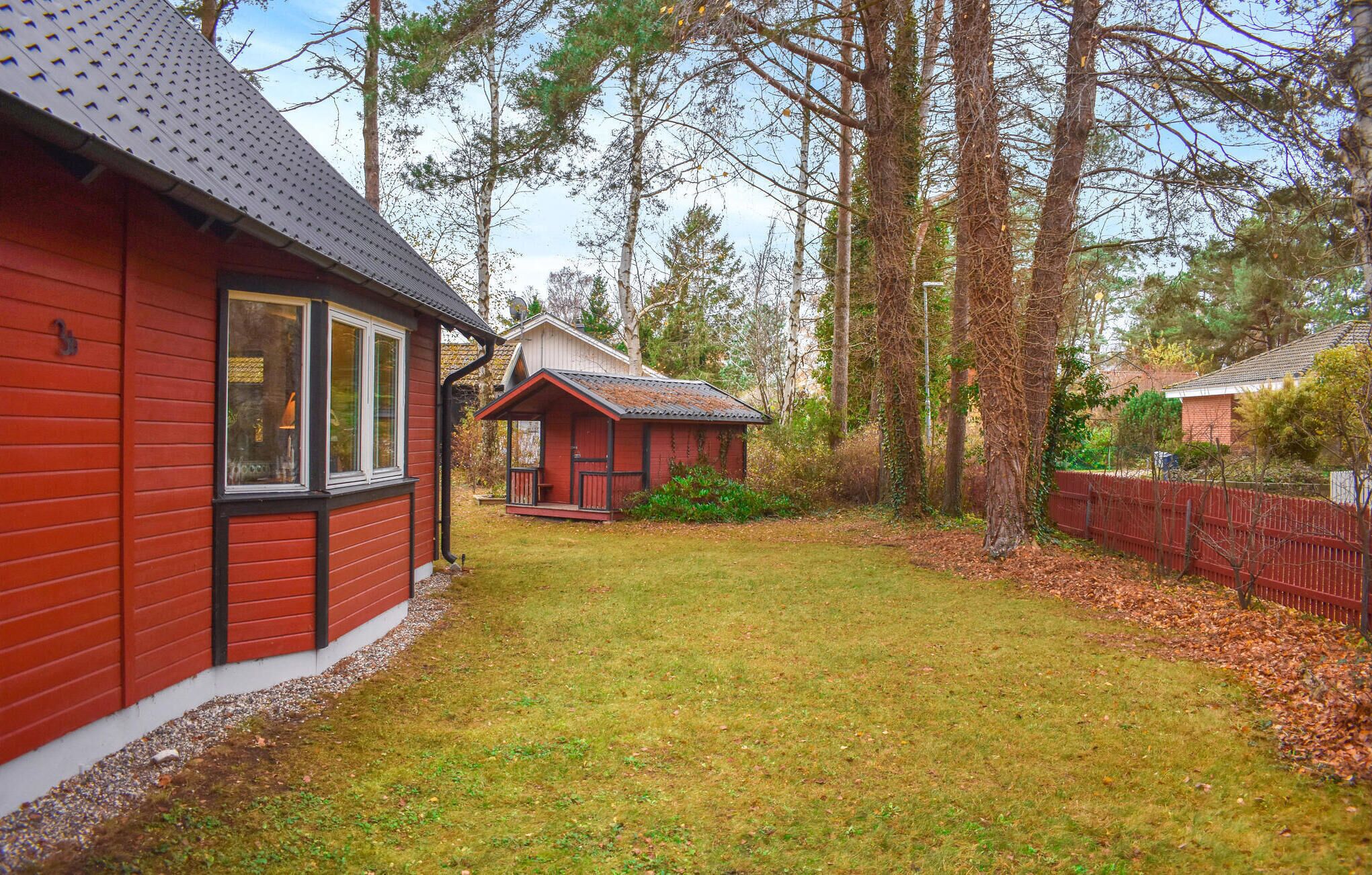 Ein rotes Holzhaus mit einer kleinen Veranda und einem Garten.