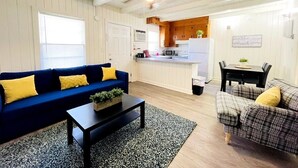 A living room with a blue sofa, a plaid sofa, a coffee table, and a ceiling fan.