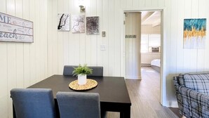 A dining area with a table, chairs, and a plant centerpiece. There are wall art pieces and a painting on the walls.