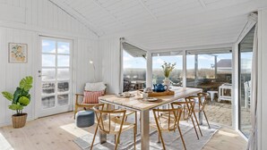 Un comedor amplio y luminoso con una mesa y sillas de madera, ventanas grandes y vistas al exterior.