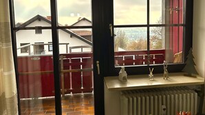 Habitación con un ventanal grande que da a un edificio rojo y una vista de la ciudad.