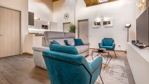 Uma sala de estar moderna com um sofá cinzento, poltronas verde-água e uma mesa de centro.