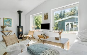 Un salon chaleureux avec une cheminée, un téléviseur et une vue sur une maison bleue.