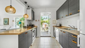 A modern kitchen with dark cabinetry, wooden countertops, and a view to an outdoor patio.