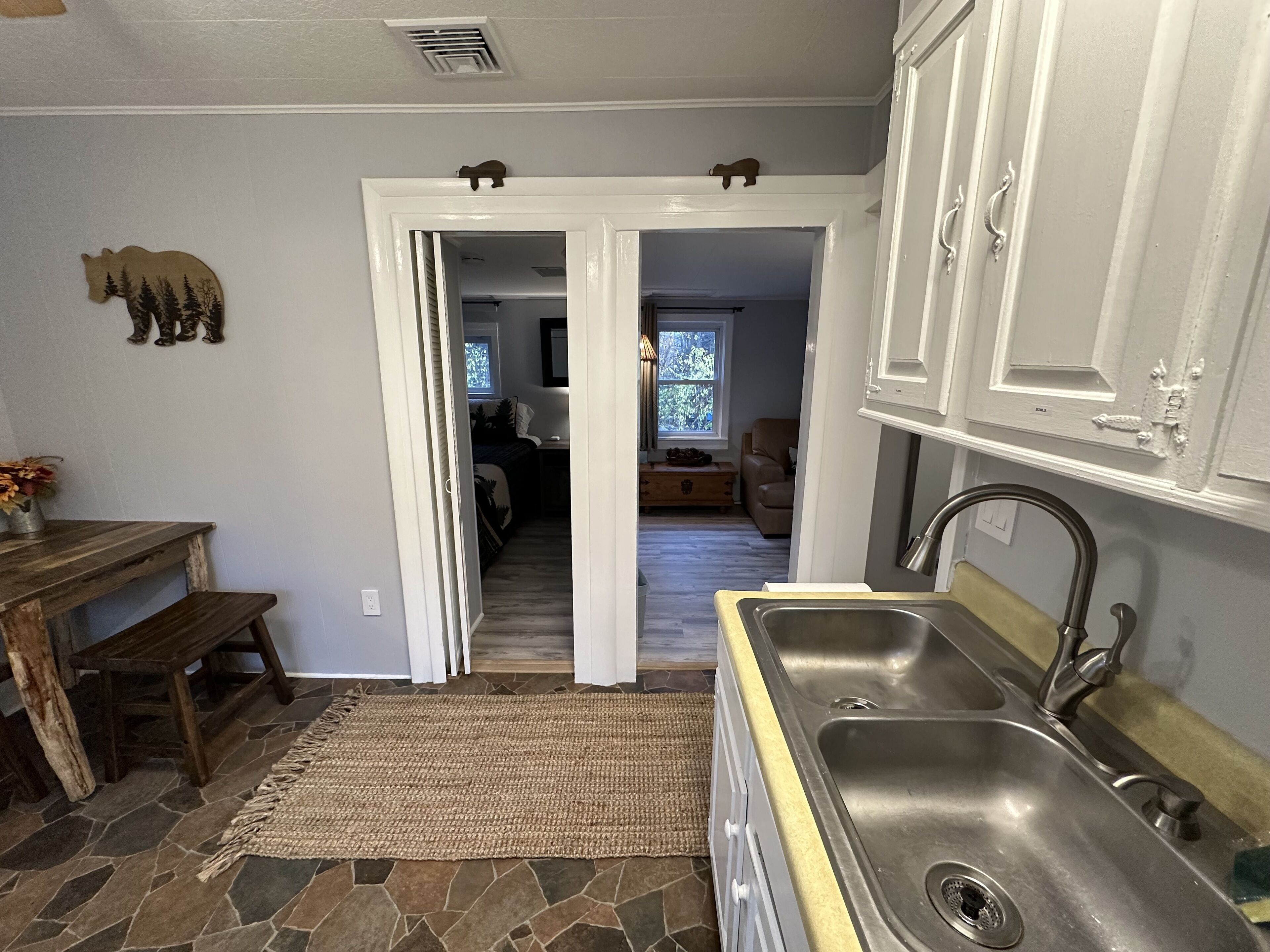 Une cuisine avec un mur recouvert de pierres apparentes, une table en bois et un tapis.