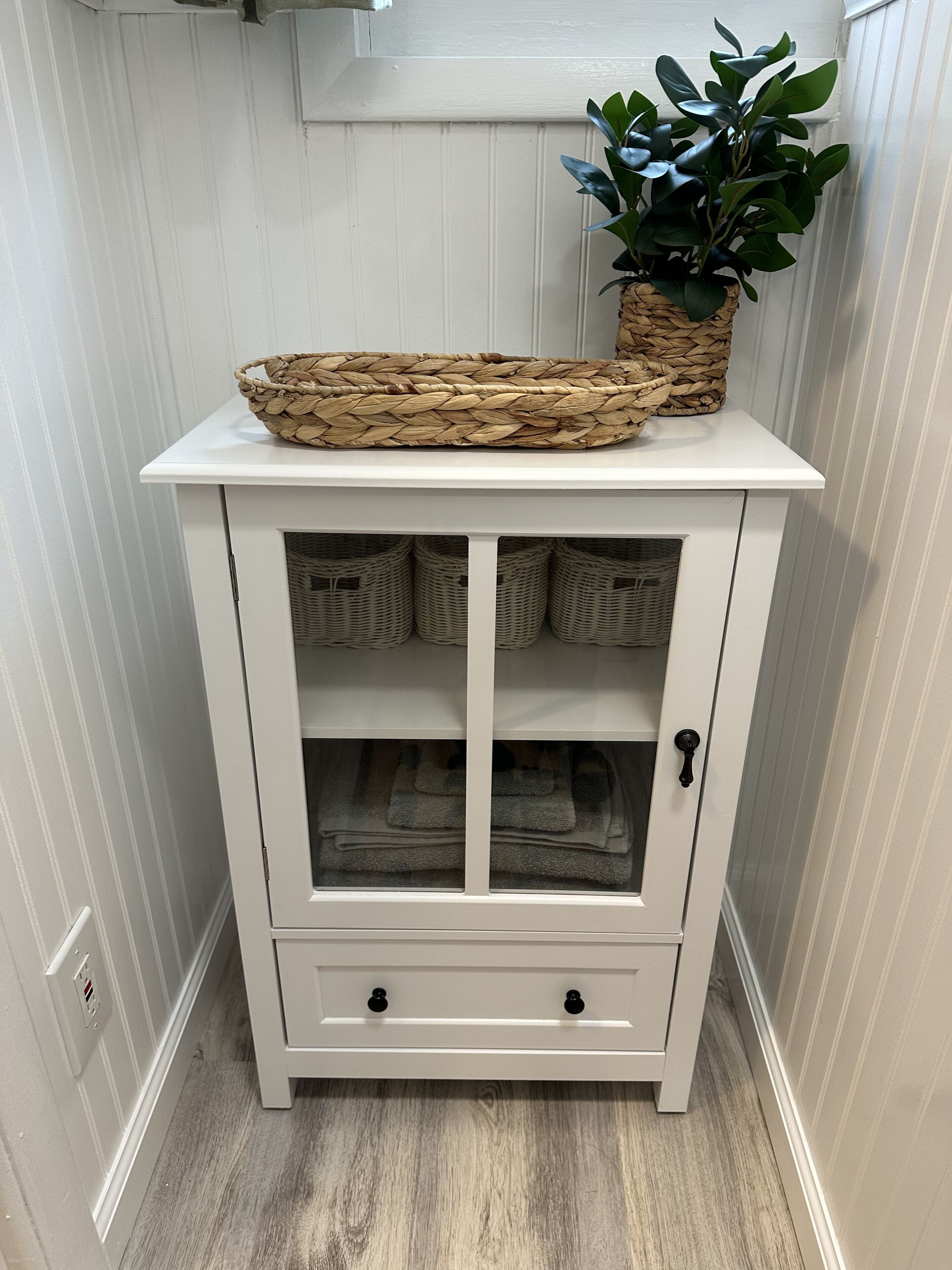 A white wooden cabinet with two doors, a shelf, and a drawer.