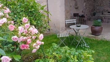 Un espace jardin aménagé avec une table et des chaises, entouré d’une végétation luxuriante et de plantes en fleurs.