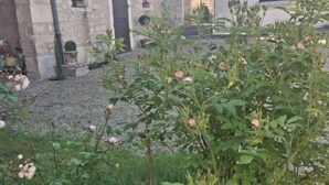A courtyard with stone buildings, a gravel path, and flowering plants. - Les Peupliers - Poilly (Poilly)