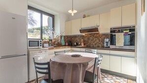 A compact kitchen with a dining area, a refrigerator, a microwave, a sink, and a stove. - Les Peupliers - Poilly (Poilly)
