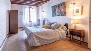 A bedroom with a bed, bedside table, lamp, and a painting on the wall. - Les Peupliers - Poilly (Poilly)