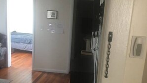 Ein Zimmer mit Holzboden, einem schwarzen Schrank, einer weißen Wand mit einem gerahmten Bild und einer Tür zu einem anderen Raum.
