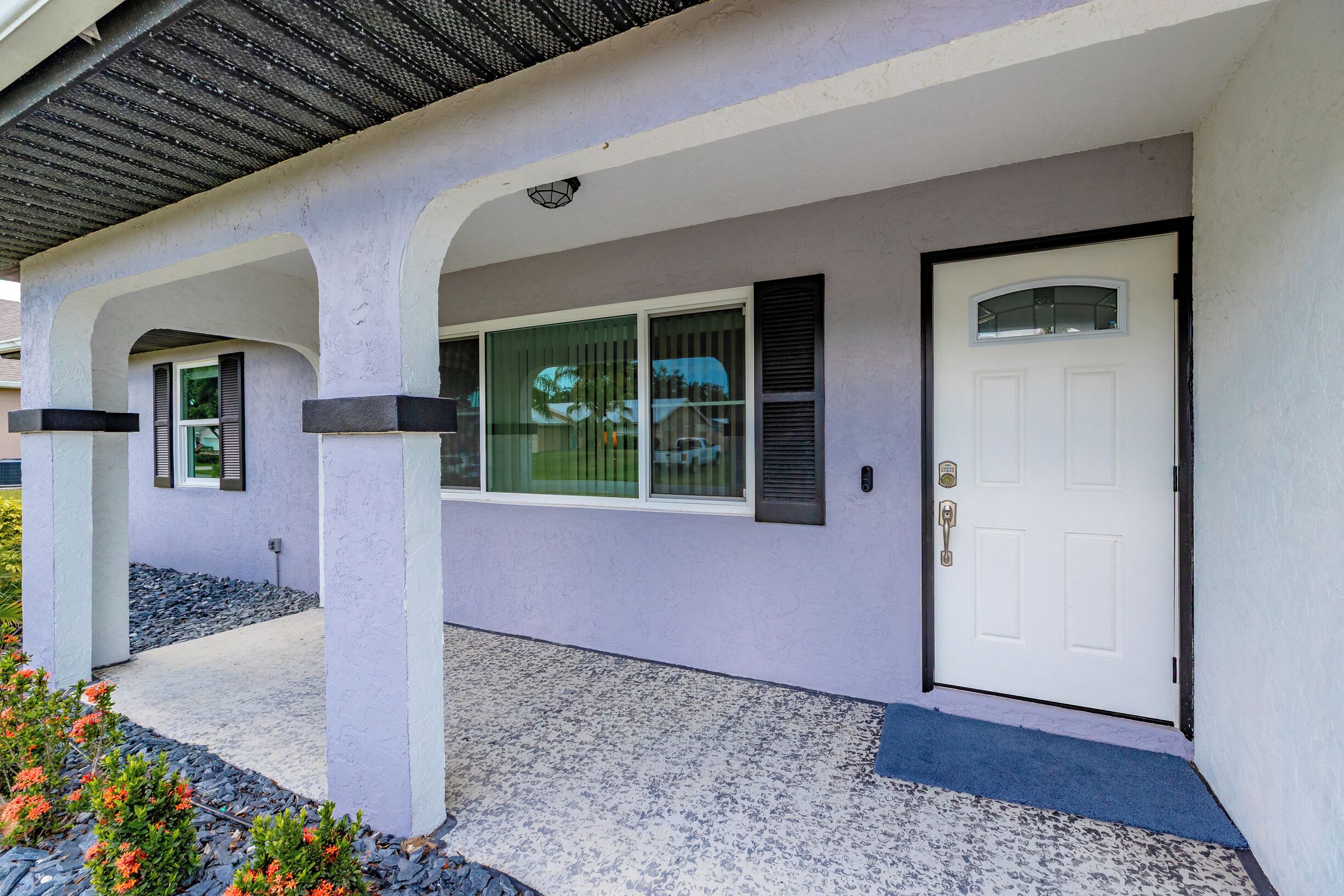 A house with a covered porch, a white door, and a window with shutters.