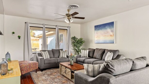 A spacious living room with two grey sofas, a wooden coffee table, and a ceiling fan. - Urban Escape! Massive home in Central Bakersfield! (Bakersfield)