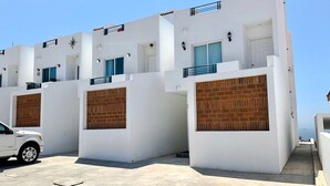 Un immeuble moderne à plusieurs étages, aux façades blanches et aux éléments décoratifs en briques.