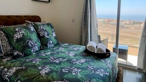 Une chambre avec un lit, un tableau encadré au mur, une fenêtre donnant sur le paysage et un plateau avec des serviettes.