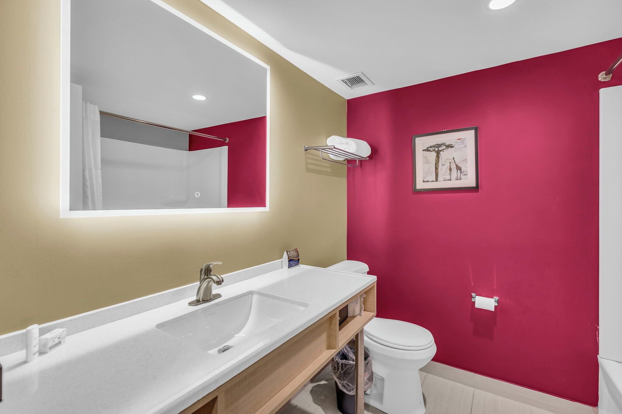 A modern bathroom with a white sink, a large mirror, and a toilet.