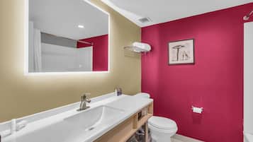 A modern bathroom with a white sink, a large mirror, and a toilet.