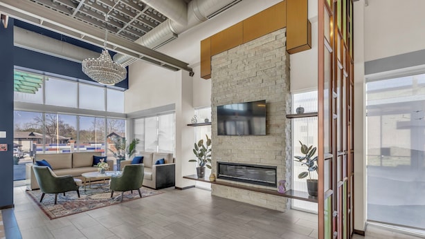 A spacious living area with a fireplace, comfortable seating, and large windows offering views of the outside. - Baymont by Wyndham Kansas City North (North Kansas City)