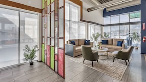 A spacious lobby with a large sofa set, a coffee table, and potted plants. - Baymont by Wyndham Kansas City North (North Kansas City)