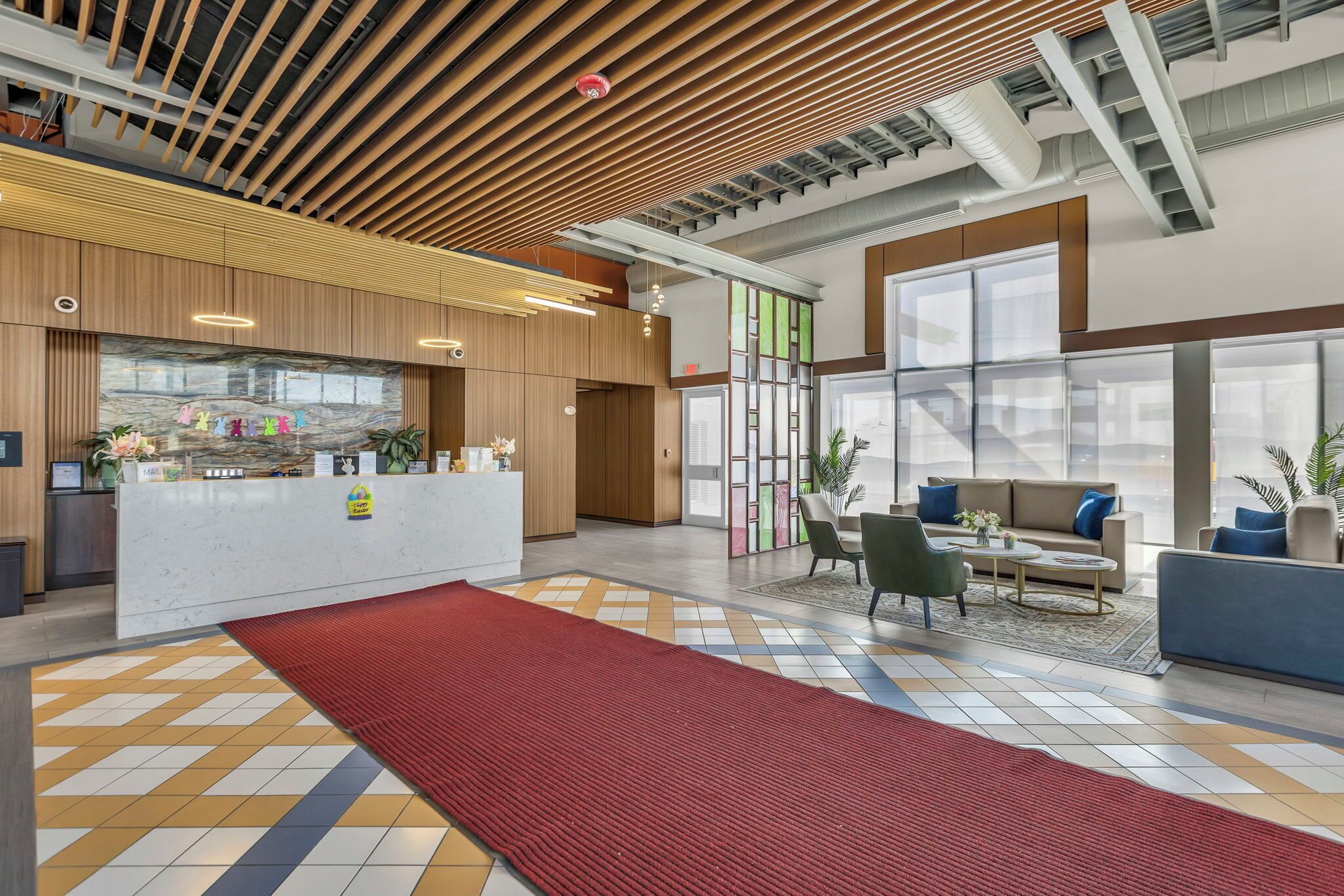 A modern lobby with a reception desk, seating area, and large windows.