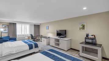 A hotel room with a bed, a desk with a TV, a coffee machine, and a small cabinet.