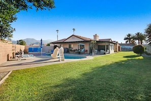 Una propiedad residencial con piscina, terraza cubierta y césped bien cuidado.