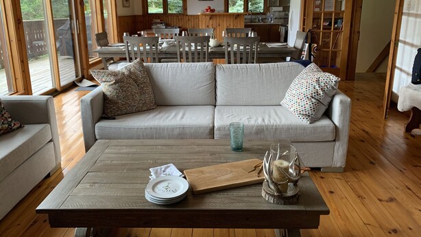 A cozy living room with a sofa, a wooden coffee table, and a dining area with a table and chairs.