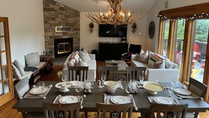 A dining area with a stone fireplace, a modern chandelier, and a cozy seating arrangement.